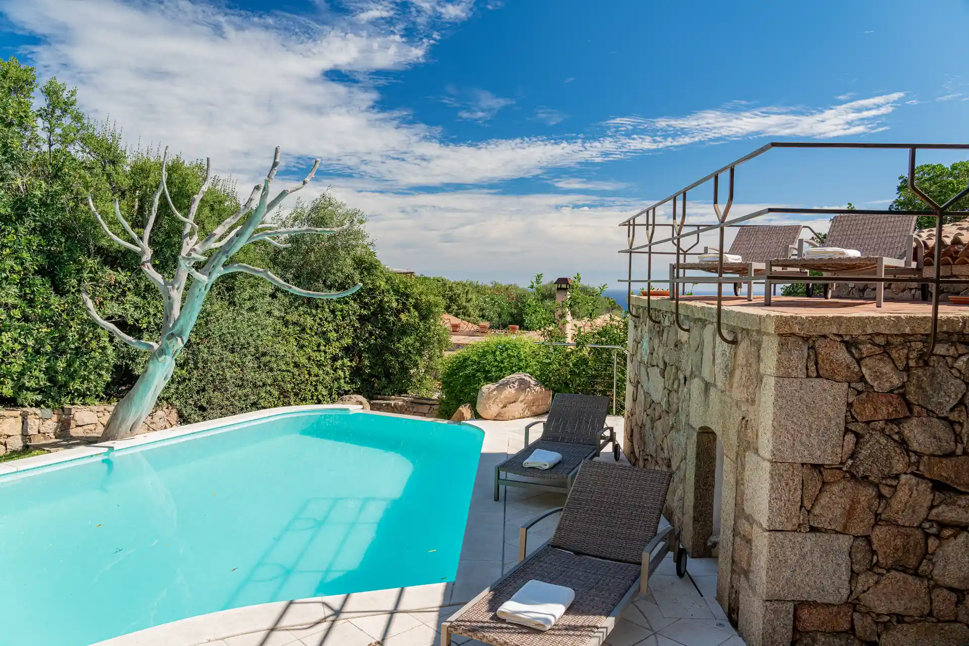 Piscina con sdraio e scultura, vista mare
